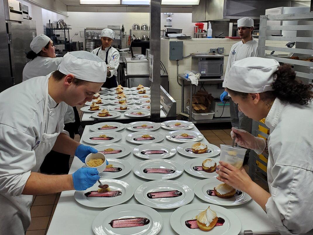 Students work in tandem to plate dessert.